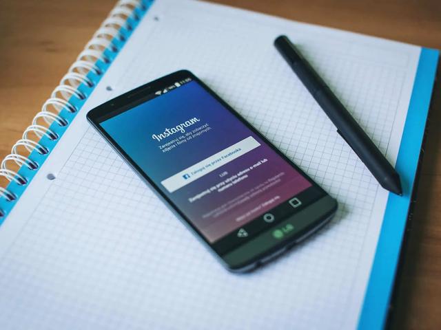 Un teléfono con la pantalla de inicio de sesión de Instagram sobre un cuaderno espiral junto a un bolígrafo