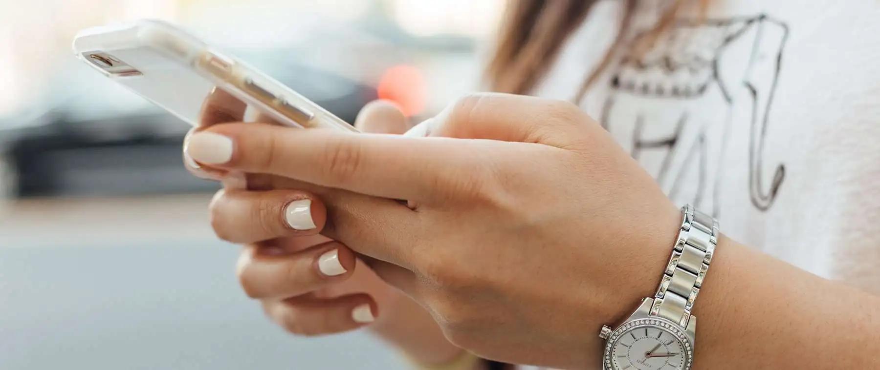 Primer plano de las manos de una mujer sosteniendo un teléfono con funda transparente