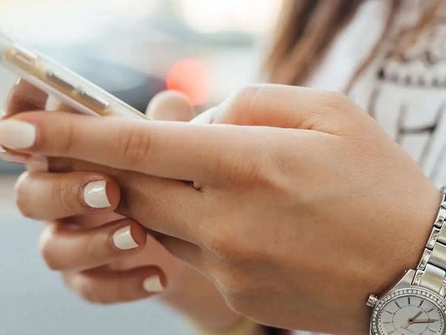 Primer plano de las manos de una mujer sosteniendo un teléfono con funda transparente