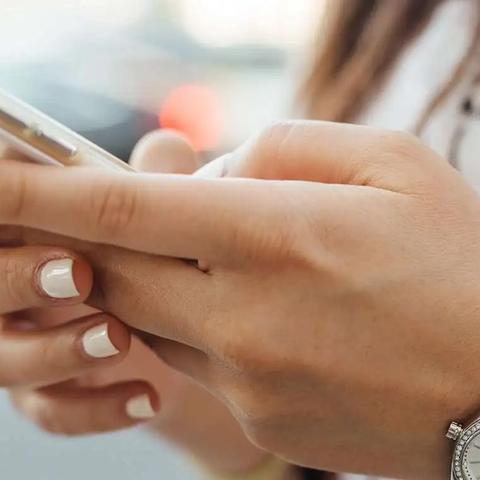 Close-up of a woman's hands holding a smartphone with a clear case