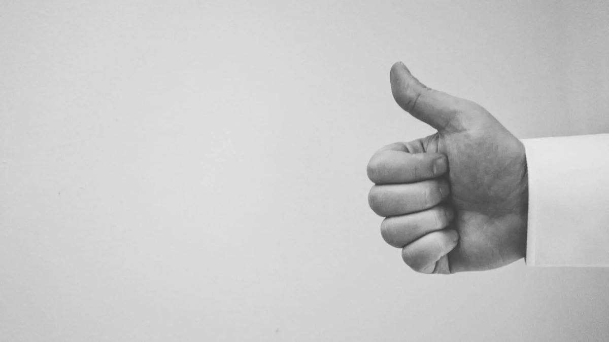 Black and white photo of a hand giving a thumbs up gesture against a plain background