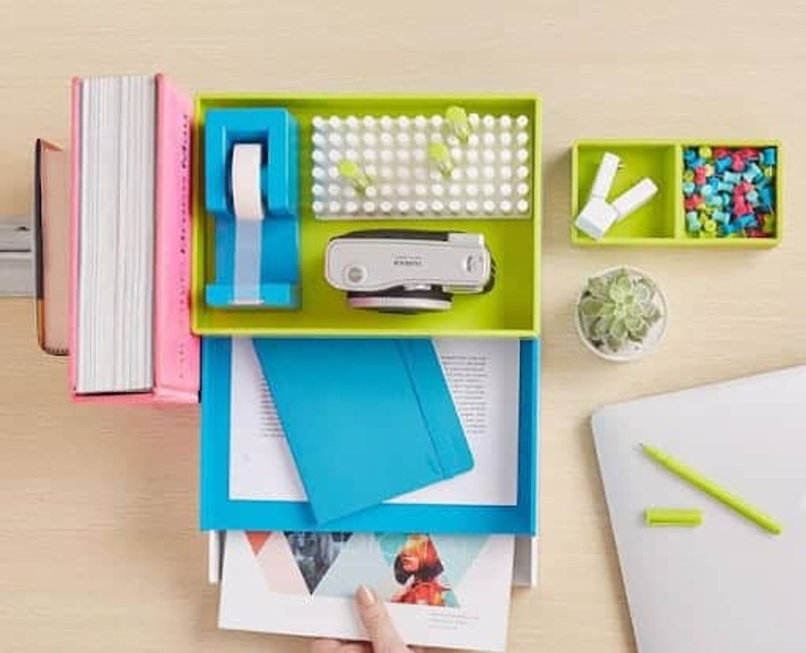 Foto cenital de un escritorio con organizadores de colores, una grapadora, cinta adhesiva, carpetas y una suculenta.