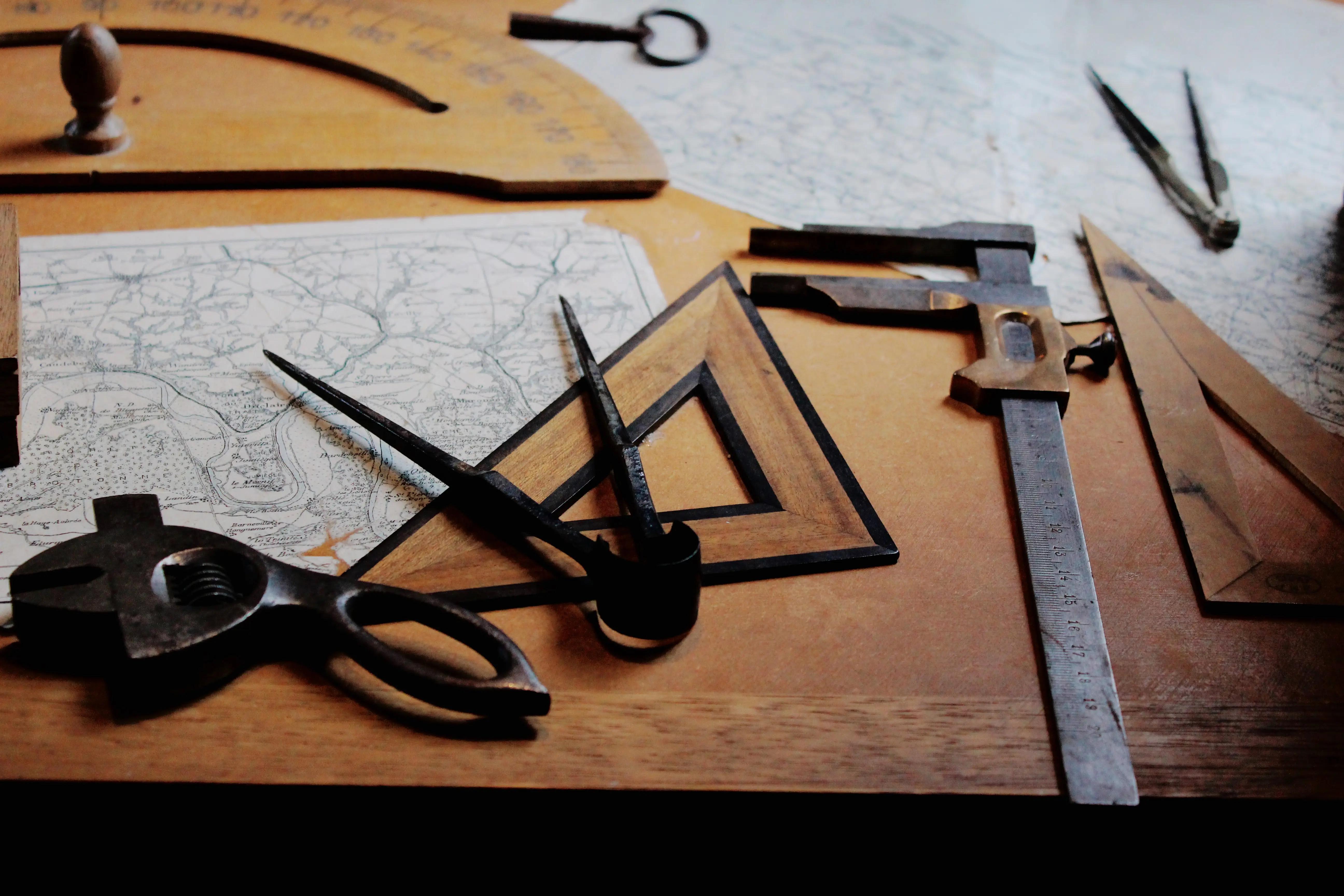 Old maps, compasses, a ruler and drafting tools laid out on a wooden desk