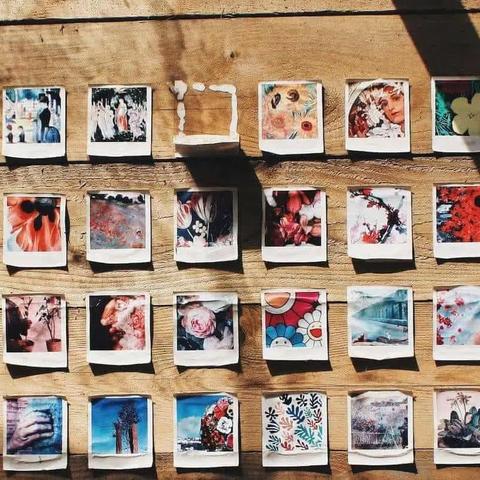 Grid of colorful polaroid photos pinned to a wooden wall in rows