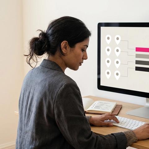 Social media manager at a head-office desk comparing store locations on a dashboard with map pins, a league table and scorecards