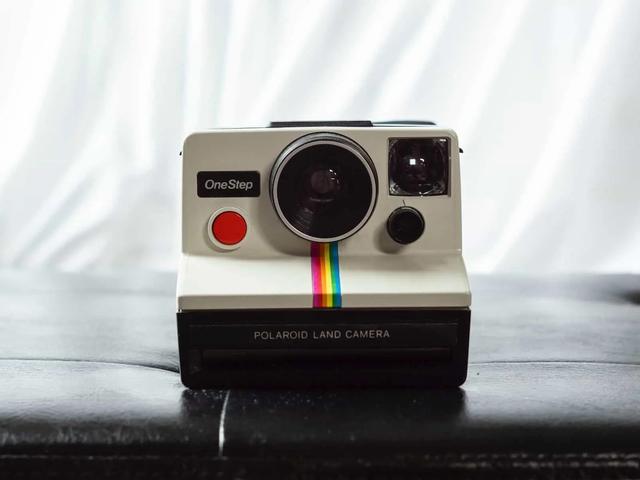 Una cámara Polaroid OneStep vintage con una franja de arcoíris, sobre una superficie oscura