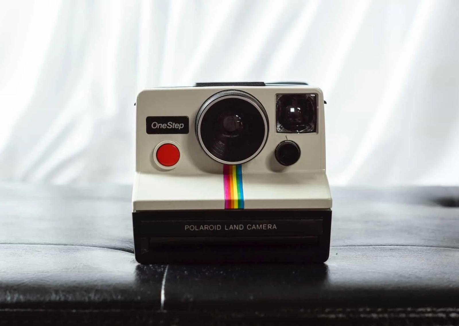 Una cámara Polaroid OneStep vintage con una franja de arcoíris, sobre una superficie oscura