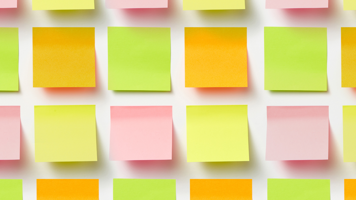 Cuadrícula de notas adhesivas de colores sobre un fondo blanco. Las notas son rosas, amarillas, verdes y naranjas. Ambiente brillante y organizado.