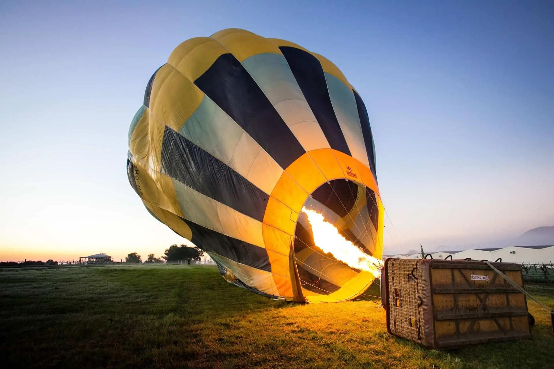 Un globo aerostático inflándose con la llama de un quemador en un campo al amanecer