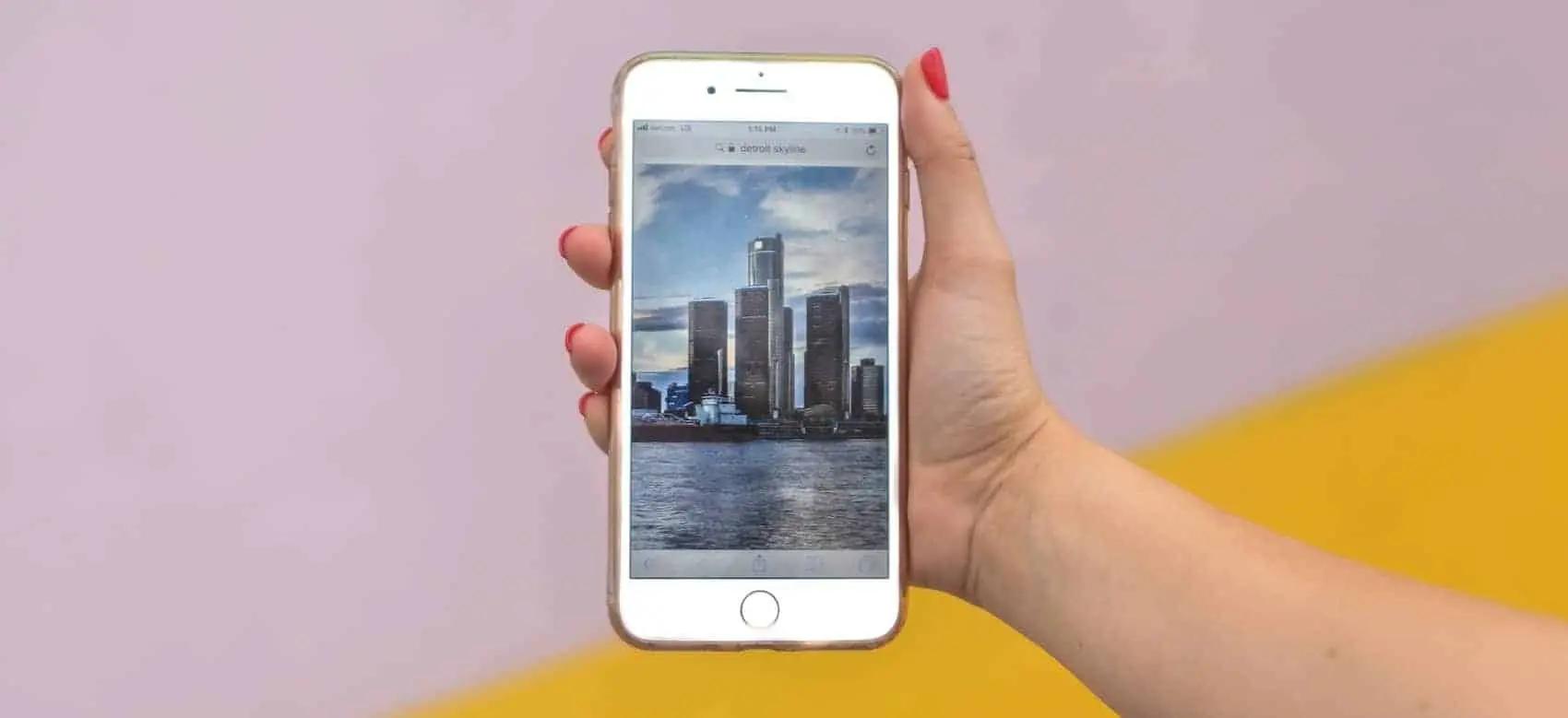 Una mano sostiene un teléfono que muestra una foto del perfil de una ciudad junto al agua