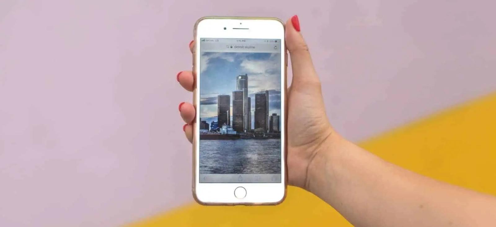 Una mano sostiene un teléfono que muestra una foto del perfil de una ciudad junto al agua