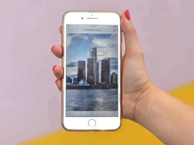 Una mano sostiene un teléfono que muestra una foto del perfil de una ciudad junto al agua