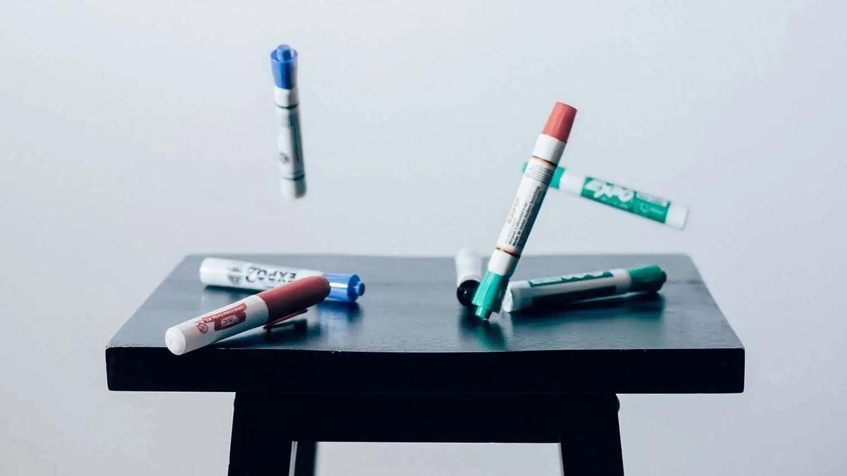 Colored markers scattered on and floating above a small black stool