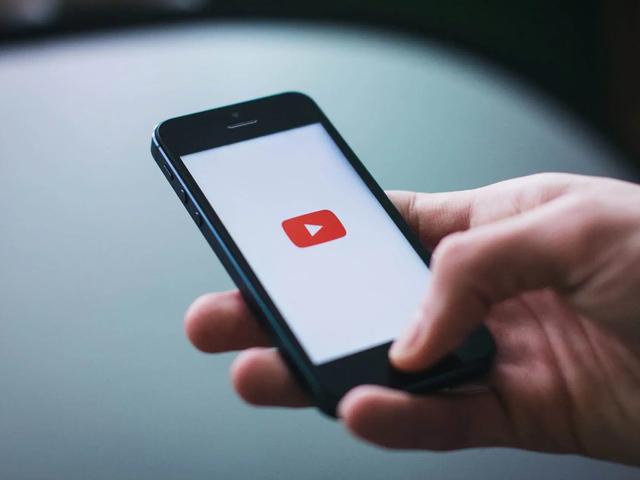 Una mano sostiene un smartphone que muestra el logotipo de reproducción de YouTube en la pantalla