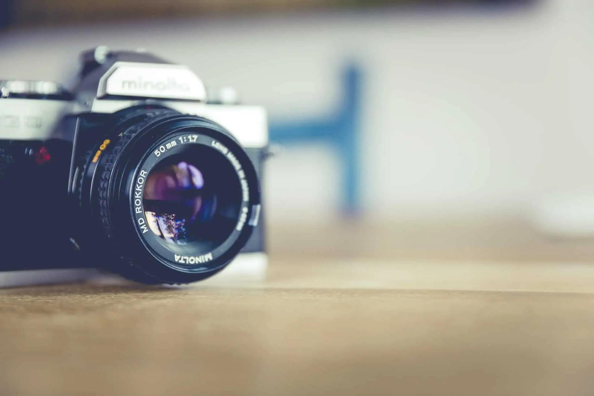 Una cámara analógica Minolta con lente de 50mm sobre una superficie de madera