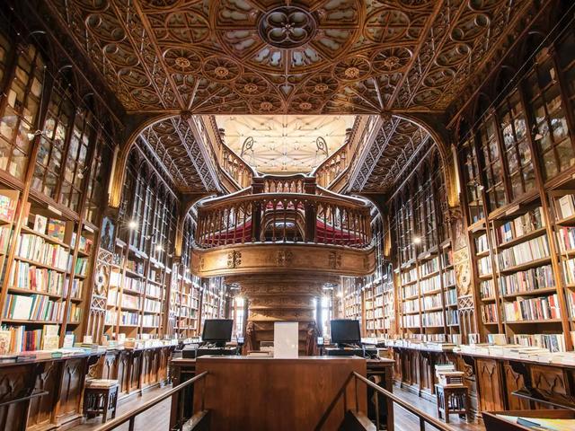 Ornate wooden library interior with a grand staircase, carved ceiling, and bookshelves filled with books. Warm, inviting mood.