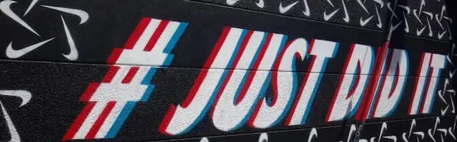 Un mural con logos de Nike y un texto estilizado que dice hashtag Just Did It