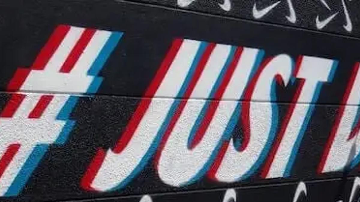 A wall mural with Nike swoosh logos and stylized text reading hashtag Just Did It