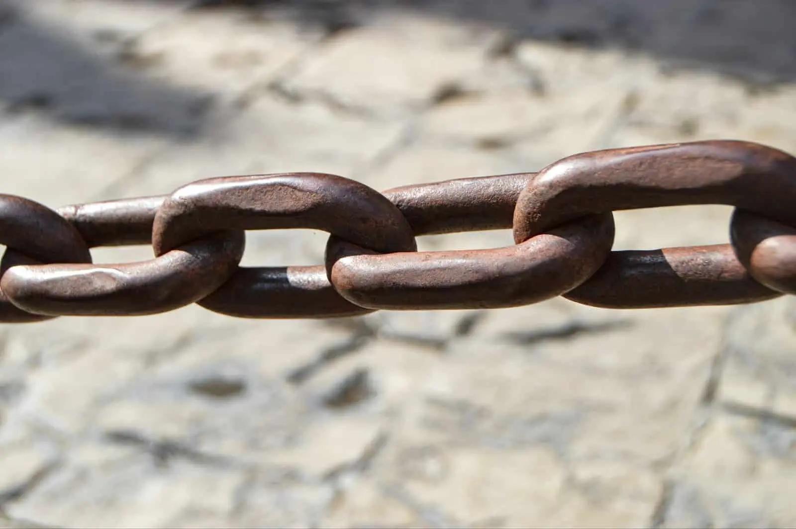 Close-up of a thick metal chain with interlocking rusty links