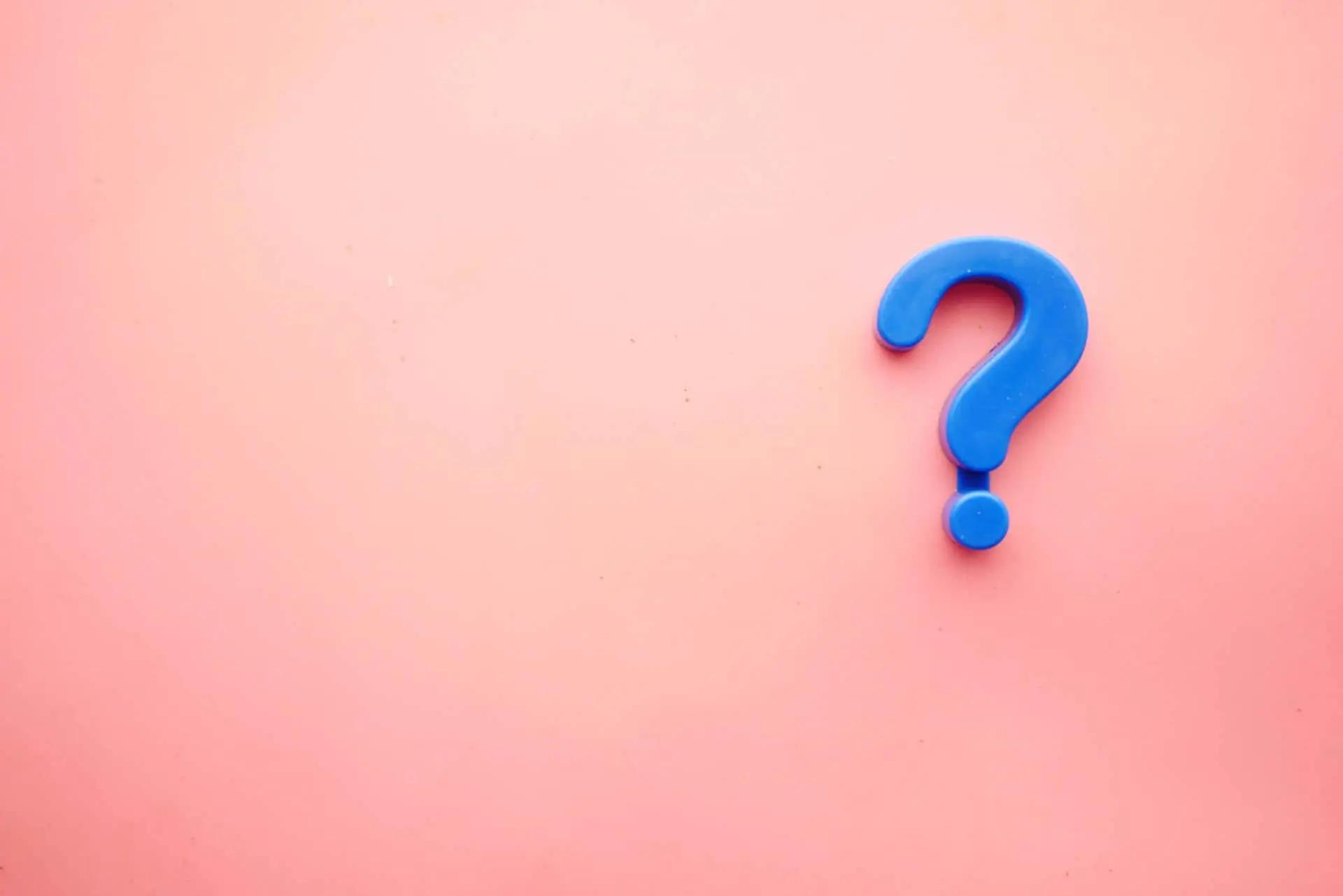 A blue 3D question mark on a plain pink background