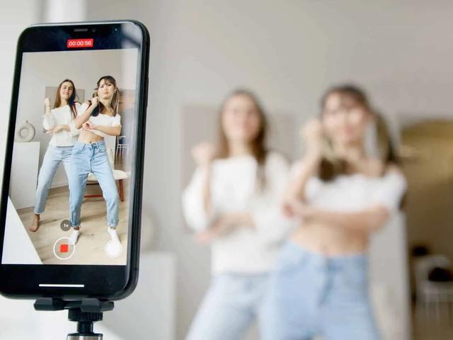 Un telefono en un tripode grabando a dos mujeres bailando una coreografia