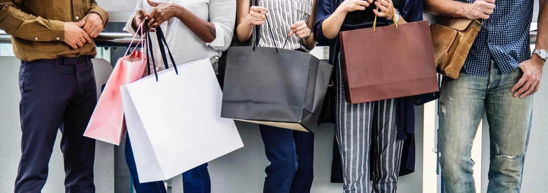 Grupo de personas de pie sosteniendo bolsas de compras de varios colores