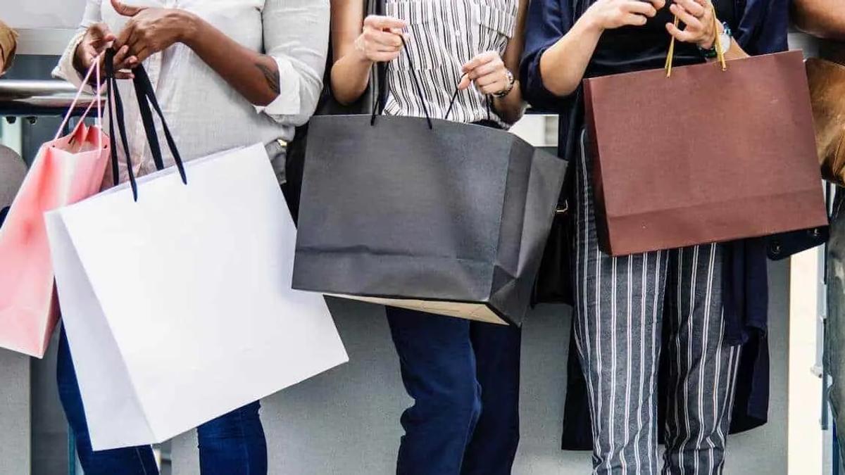 People standing in a row holding colourful shopping bags