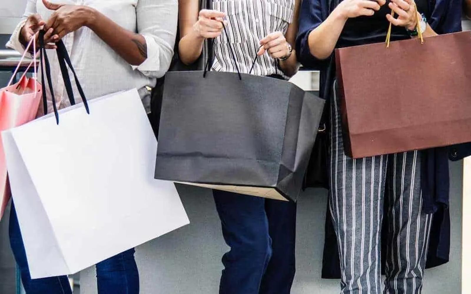 People standing in a row holding colourful shopping bags