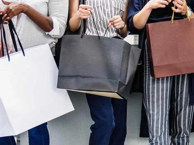 Grupo de personas de pie sosteniendo bolsas de compras de varios colores