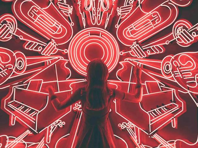 Una mujer de espaldas frente a un mural de neón rojo con instrumentos musicales simétricos