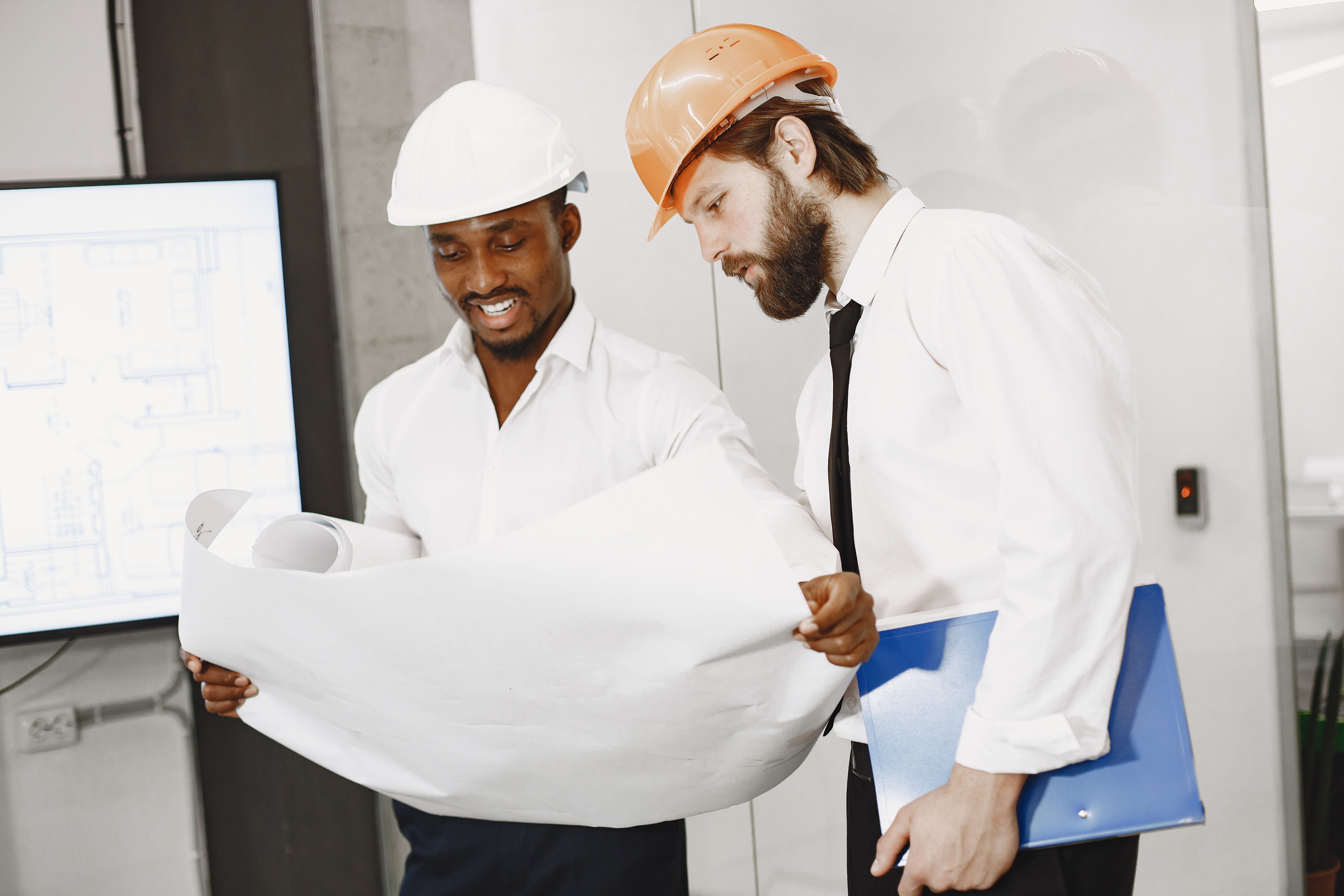 Two people in hard hats looking at a construction diagram