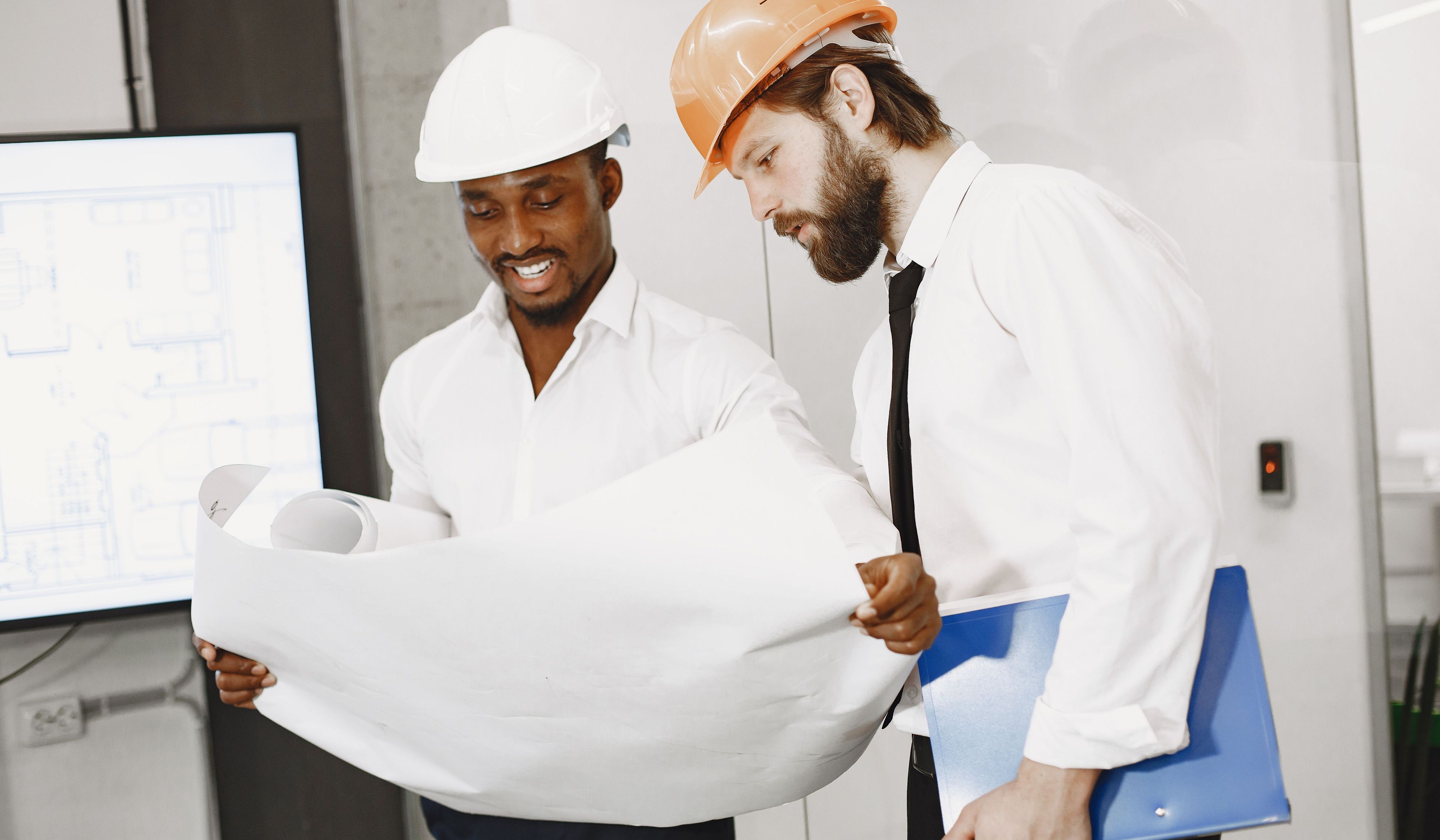 Two people in hard hats looking at a construction diagram