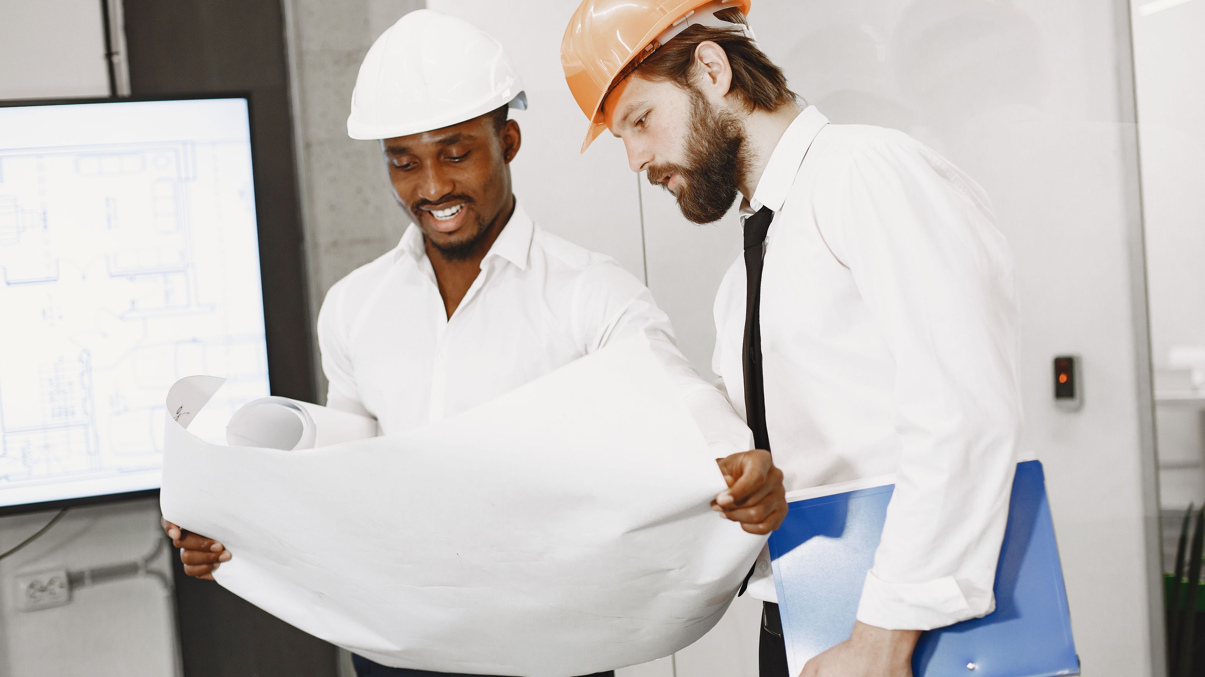 Two people in hard hats looking at a construction diagram
