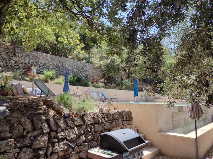 Barbecue à gaz contre le mur en pierres sèches, sous la piscine