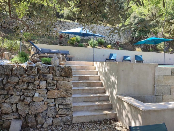 Escalier de pierre montant vers la piscine et ses parasols