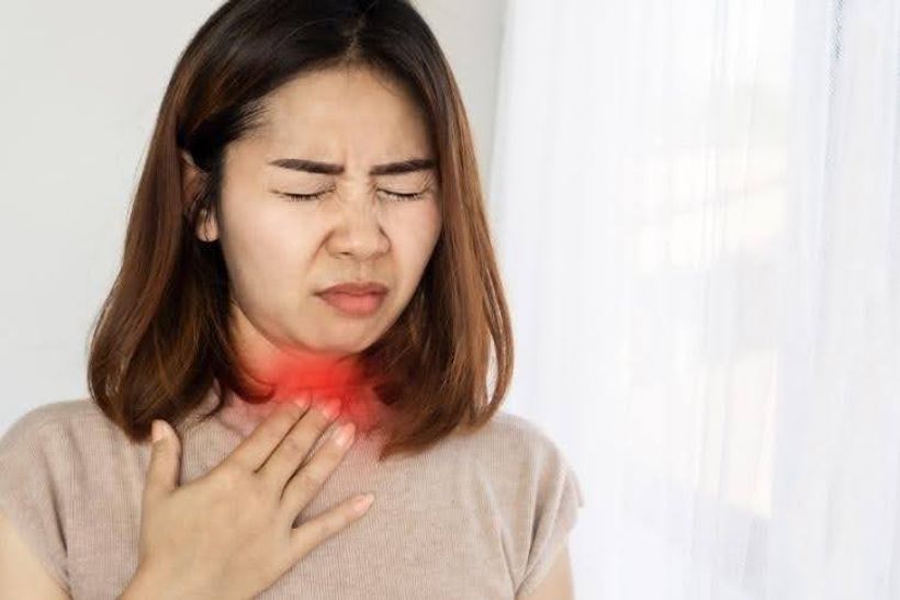 Woman experiencing a painful sore throat.