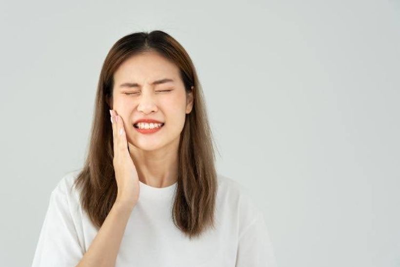 Woman holding her cheek while experiencing severe toothache.