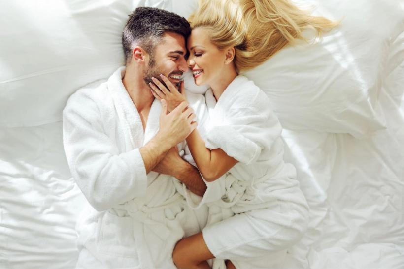 A couple smiling and cuddling in bed