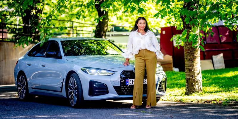 En dame som lener seg på bilen sin.