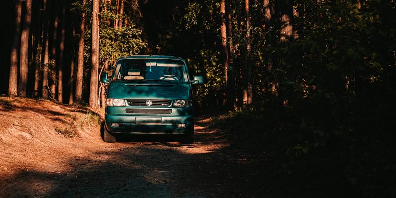 Grønn bil som er avregistrert og står parkert på en vei i skogen.