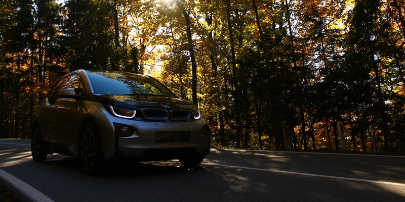 En bil som kjører på en vei gjennom skogen.