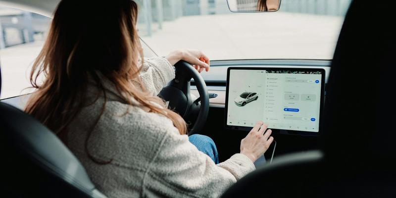 En kvinne som justerer innstillinger på bilen sin på en smartskjerm.