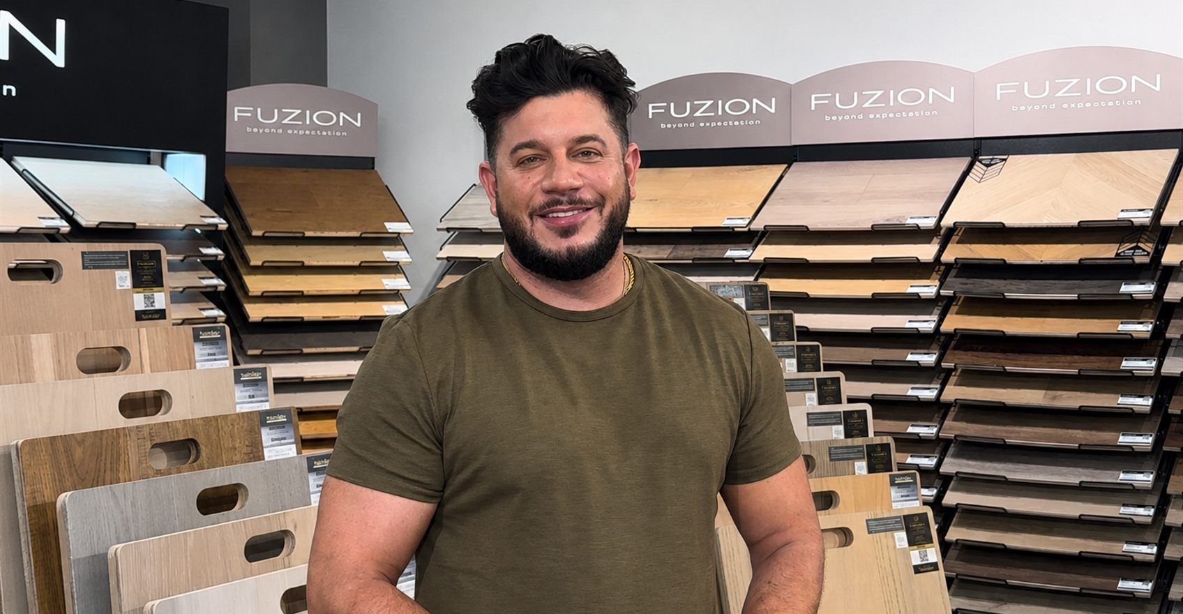 A man standing in the GreenValley showroom beside racks of flooring samples