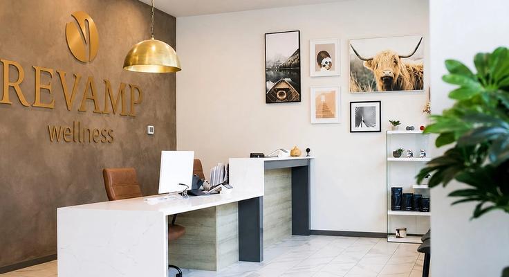 The Revamp Wellness reception desk under a brass pendant light