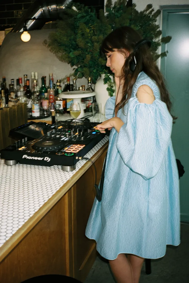 woman mixing on a dj deck in a blue dress