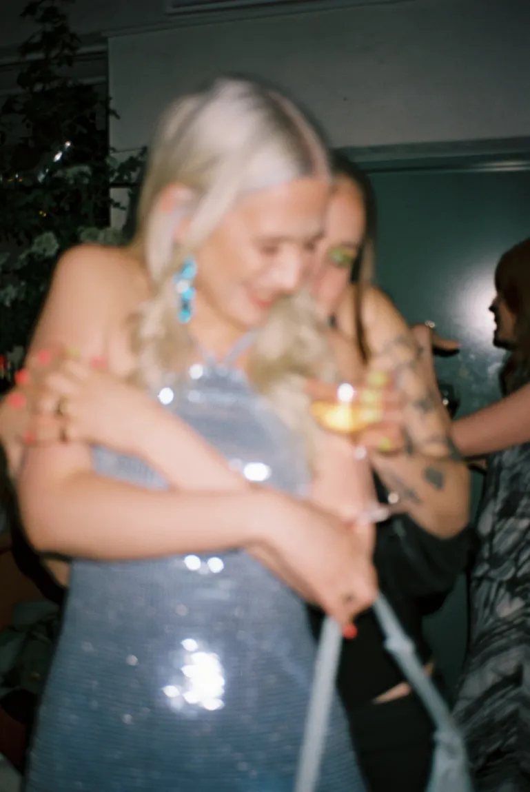 two women hugging from behind with a glass in their hands