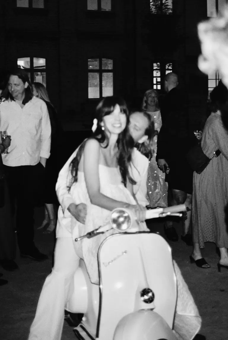 newlywed couple on a white vespa with husband giving a kiss on the cheek