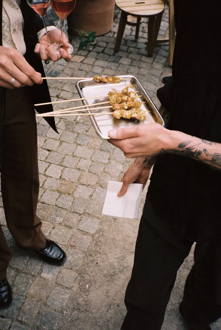 server handing out skewers on a plate to a guest outside on the patio
