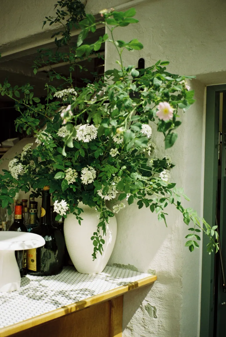 a white bouquet of flowers in the corner of asters white tiled bar top