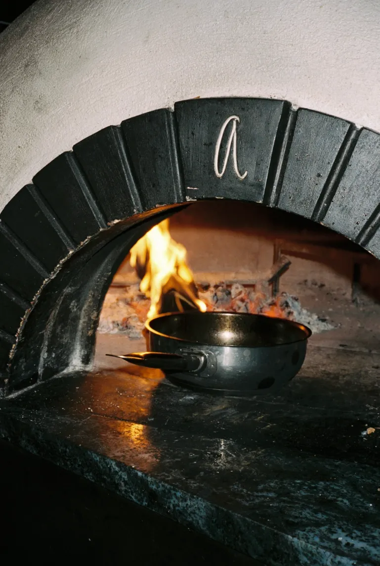 a steel pot in the hatch of asters wooden oven with a fire lit inside